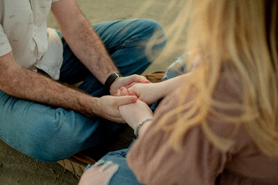 A serene moment as an engaged couple holds hands during a dreamy beach engagement session in Galveston, TX