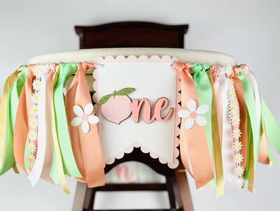 Peach birthday high chair flag with white flowers, lace, and pink and green flags