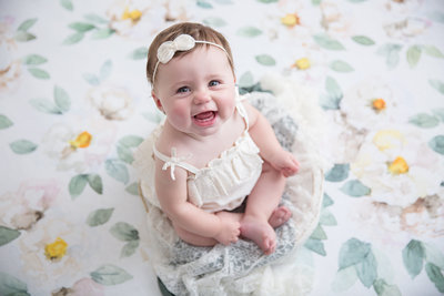 baby girl in white on floral backdrop