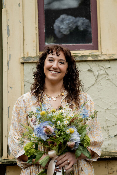Pittsburgh wedding florist Heavenly Blooms holding bouquet of flowers in front of a building exterior