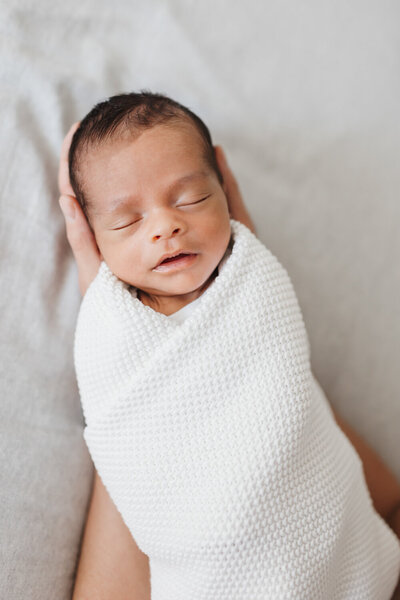Sleeping newborn baby boy who is laying in his dads large hands