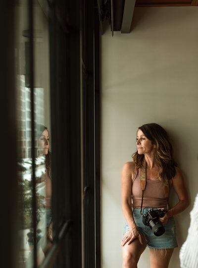 Minneapolis natural light photographer Shannon Kathleen looking out window during branding session.