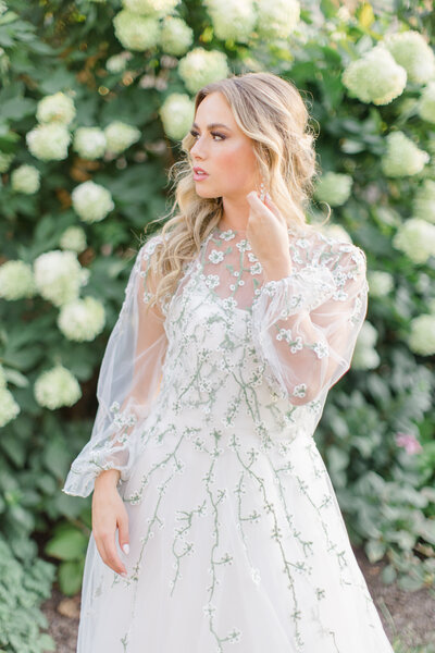 Bride posing for a portrait in a wedding dress with a sheer floral overlay