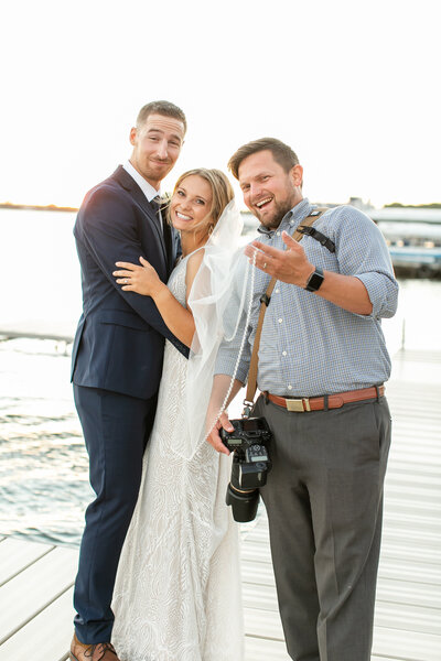 Brandon is standing next to a couple on a dock. They are all smiling into the camera