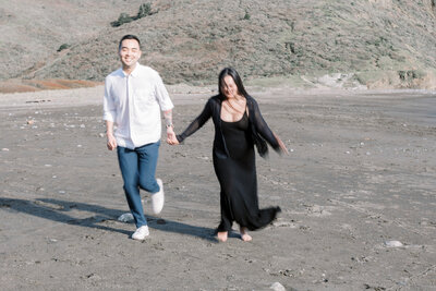 bay area photographers captures beach engagement pictures with woman piggy back riding on mans back as they both laugh