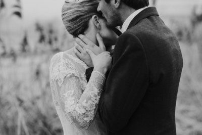 Close-up bruidspaar. Handen die elkaar vasthouden en een kus in de nek.