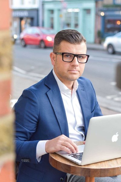 Businessman working on laptop outside a cafe in London