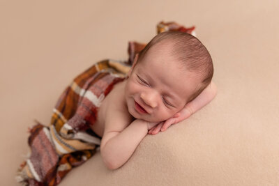 baby sleeping under plaid wrap by Philadelphia Newborn Photographer