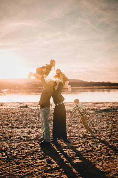 A family laughs and embraces the chaos with happy keepsakes from their fall family session along the Missouri river near Bismarck, ND.