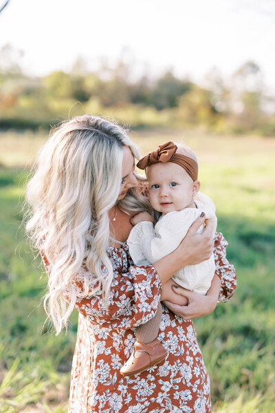 Mom in red floral dress holds infant daughter in her arms near the PA Appalachian mountains\