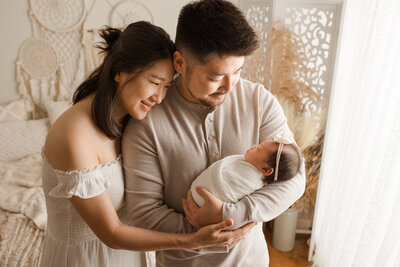 newborn baby girl posing with her parents during her newborn session