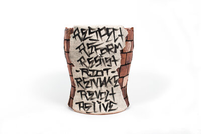 A ceramic cup that resembles plaster falling apart from red bricks with painted cacti and graffiti