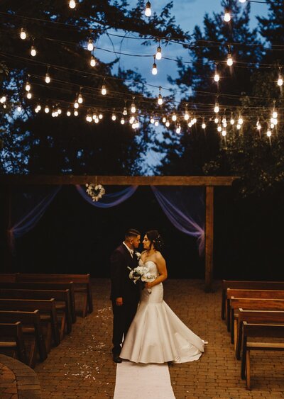 Couple standing under twinkling lights after ceremony