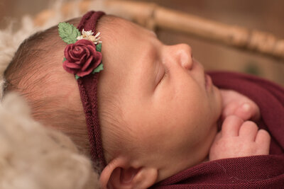 Baby girl wrapped in red backdrop with red rose headband