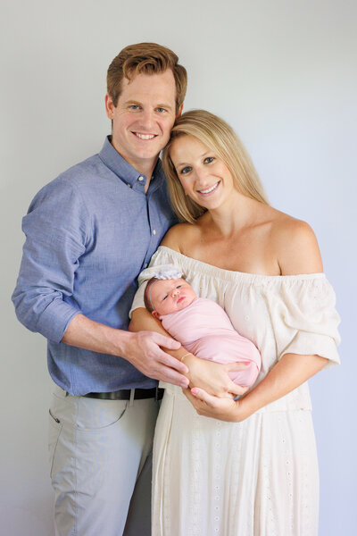 Two women standing next to each other with a child in one of their arms and a small child standing in front of them