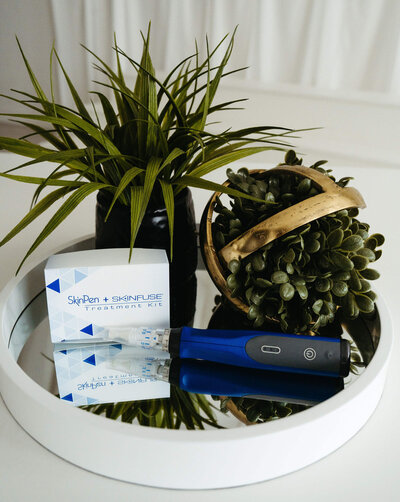 SkinPen microneedling device and Skinfuse skincare displayed with greenery, representing treatment tools at Maxwell Aesthetics Salem