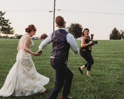 Couple and Photographer running on wedding day.