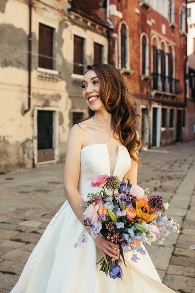 Bride in Venice holding a bouquet, exuding simple elegance against the scenic backdrop of the city's timeless charm