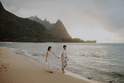 Couple walks along the shoreline at Tunnels Beach in Kauai on their elopement day