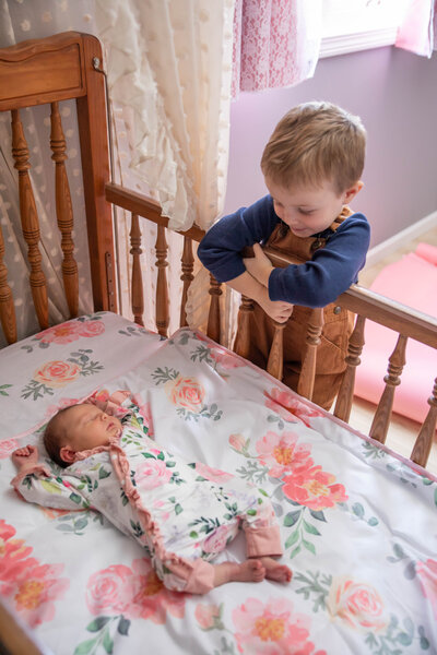 Brother starting down at newborn sister in crib | Newborn Photography Session