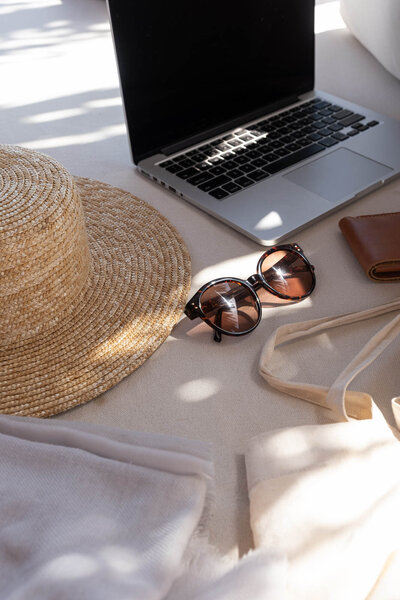 Straw beach tote, earrings and bikini next to luxury pool