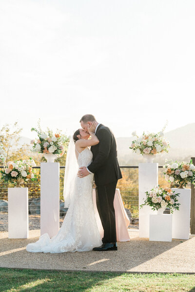 bride and grooms first kiss with mountain backdrop