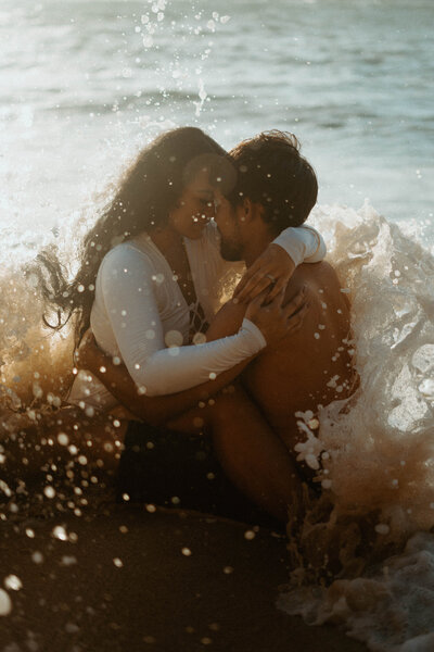 man and woman hugging while sitting on beach
