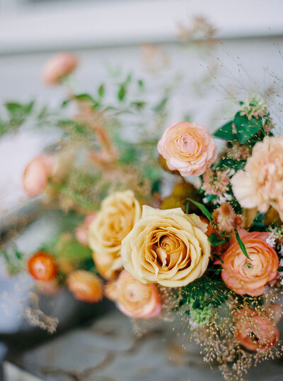 Peach and yellow wedding centerpiece with roses and ranunculus from Flowershop Charleston