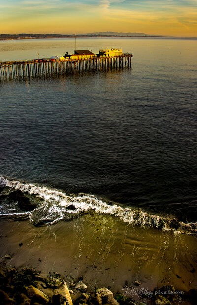 Capitola Boat & Bait and Wharf House Restaurant before the storm of January 2023 with calm surf in foreground.