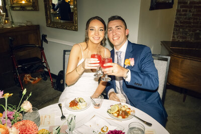 Newlyweds toast joyfully at their wedding reception dinner