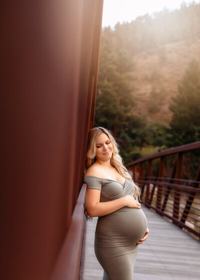 maternity photographer poses pregnant mom on stool holding her bump  for photos
