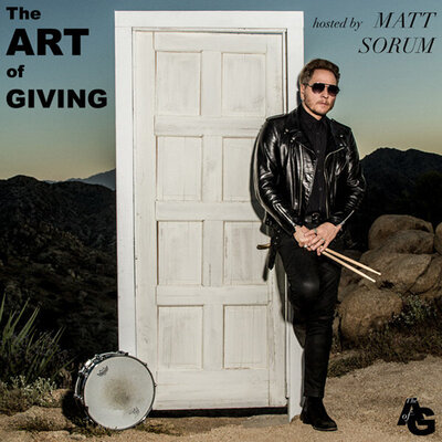Matt Sorum portrait The ART of GIVING instagram feed leaning against doorway in middle of desert holding drumsticks against thigh snare drum leaning against doorframe next to him