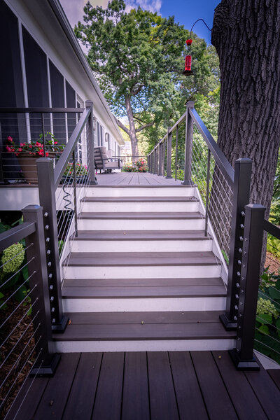 Low-maintenance deck stairs with contrasting risers and treads, with cable railing on the sides. 