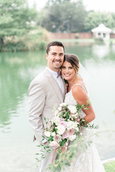 Bride and groom posing in front of pond at Light and airy wedding photography by the Best Boise Wedding Photographers