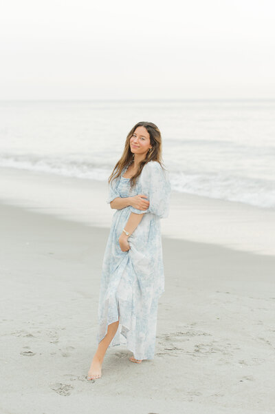 Beautiful sunrise session with a stunning brunette senior on the beach wearing a blue dress captured by Orlando senior photographer