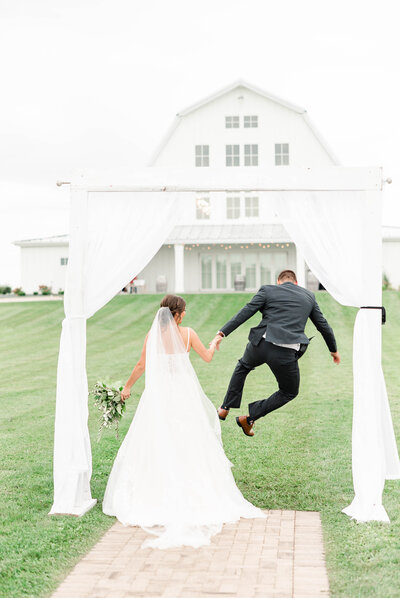 Groom does a bell kick while holding hands with his bride on their wedding day