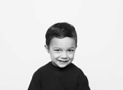 black and white image of a boy with a sheepish grin