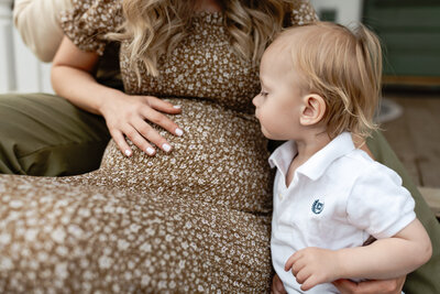 Big brother kissing his mom's pregnant belly.