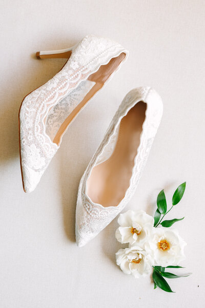white wedding shoes on flatlay with white flowers