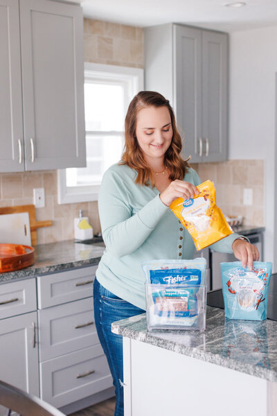 Emily organizing pantry items into clear bins in the kitchen