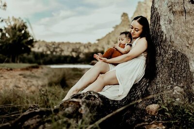 Mother and young child sitting together against a tree in golden afternoon light, captured by Family Photographer in Macon GA, illustrating the precious memories that families will treasure as children grow.