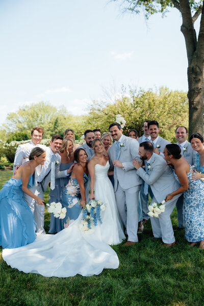 bride and groom embracing as their wedding party comes in for a group hug