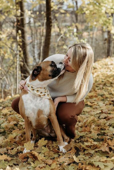 Chiropractor Brittany Fisk sitting in a grassy field with her brown boxer dog, representing Busy Bee Chiropractic’s caring approach.