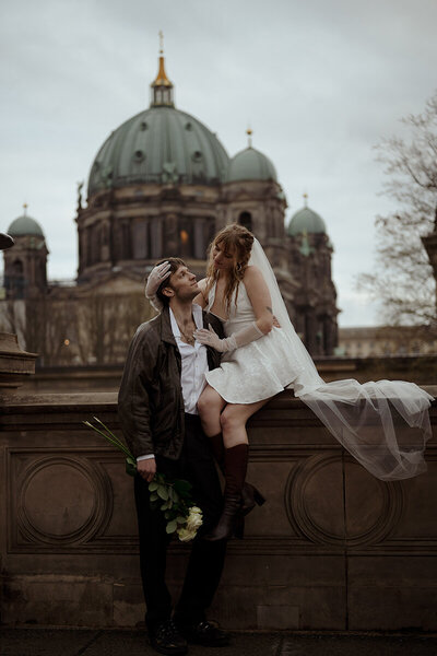 Brudpar står framför en katedral i berlin och tittar på varandra