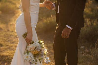 bride holding her wedding bouquet while also holding groom's hand