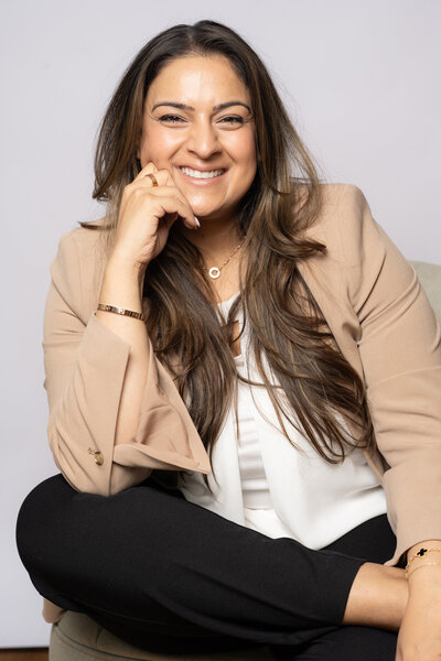 The strategies of success with Assia Mahmood, pictured in an elegant beige blazer, offering expert guidance to female entrepreneurs from the comfort of a couch