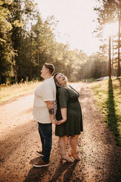LGBTQ+ couple at sunset for engagement photos  back to back in Bayfield Wisconsin