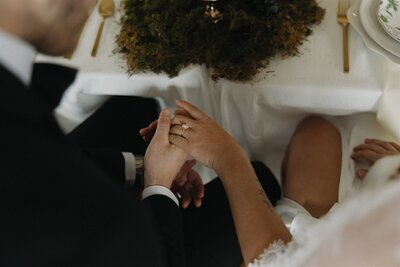 Bride and groom hold hands at wedding reception table
