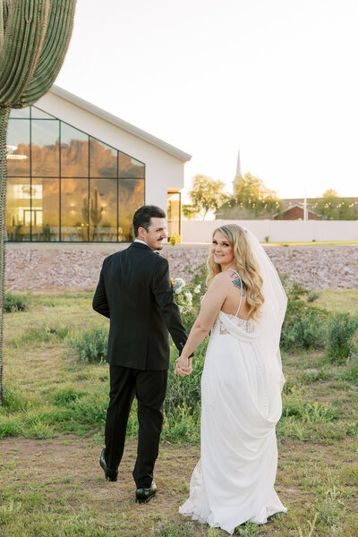 Newlyweds embrace and kiss in the midst of the desert, adorned in beautiful attire