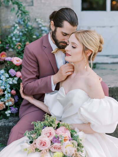 Man in purple suit is leaning into woman in bride dress